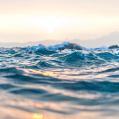 Close-up of the ocean water glistening in the sun with the sun set in the background