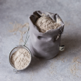 A grey bag of clay powder with a clay sifter leaning on it